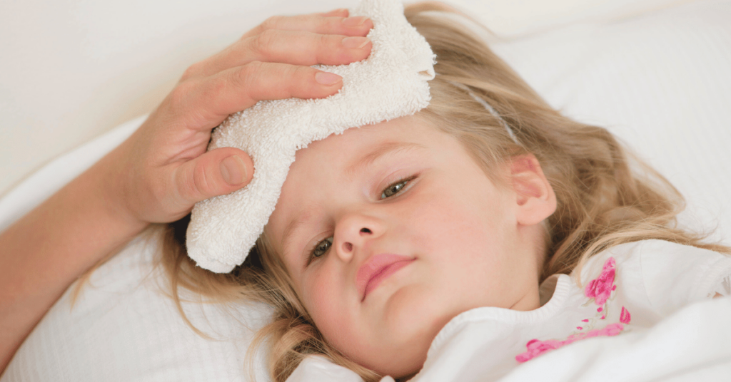 A young girl with a fever has a cool compress on her forehead.