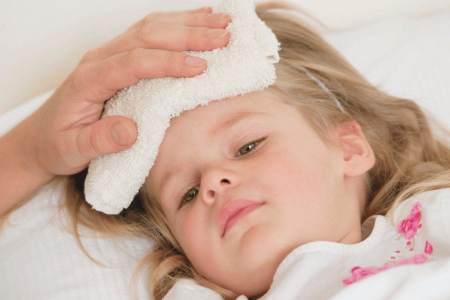 A young girl with a fever has a cool compress on her forehead.