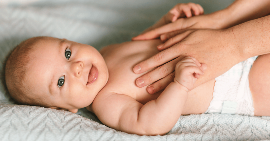 A baby wearing a diaper lays on a blue blanket.