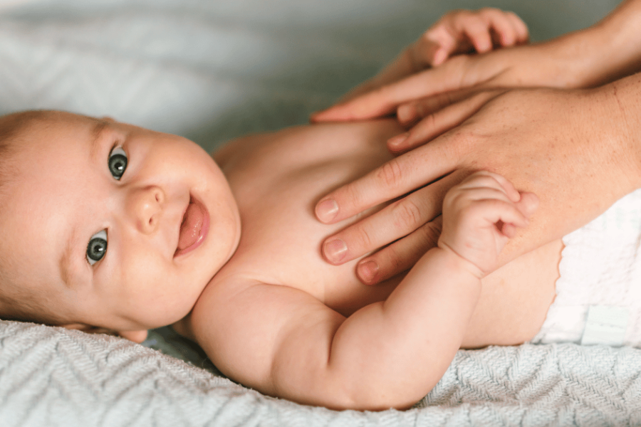 A baby wearing a diaper lays on a blue blanket.