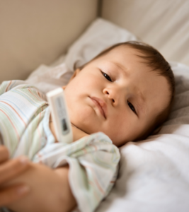 A baby gets their temperature taken under their armpit.