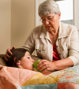 A grandma gives her sick grandchild a sip of water. 