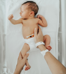 A newborn baby lays in a hospital bassinet.