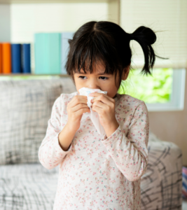 A sick girl blows her nose and coughs.