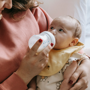 A mother feeds her baby a bottle.