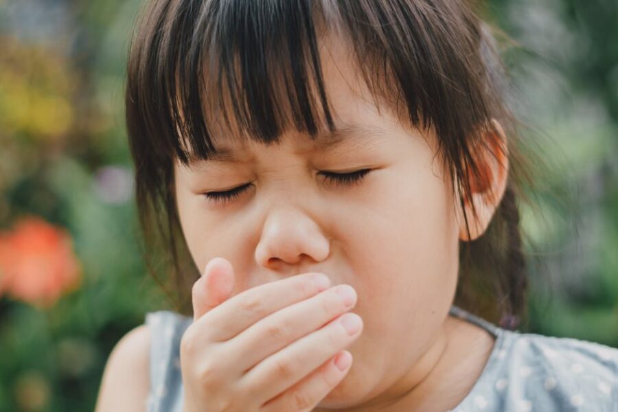 A girl coughs while outdoors.