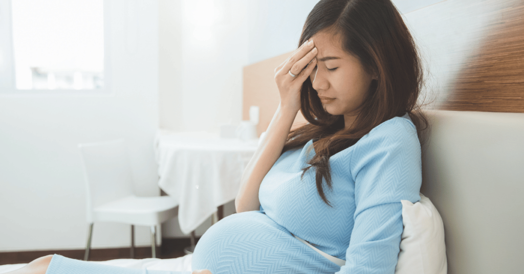 A tired pregnant woman rests on the couch.