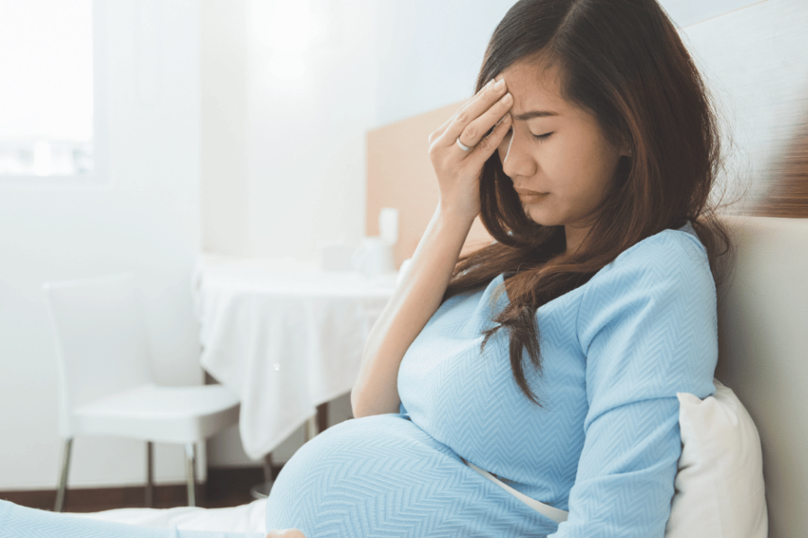 A tired pregnant woman rests on the couch.