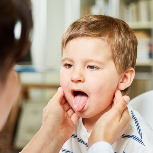 A doctor looks at a child's tonsils.