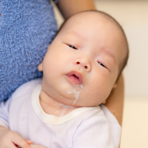 An infant has some spit up on her face.