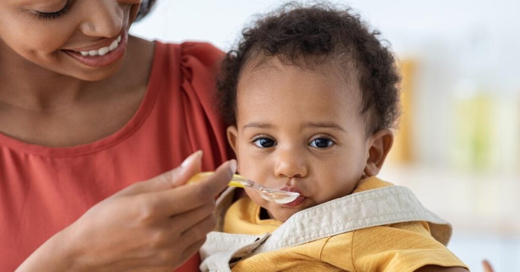 A mom feeds her baby a spoonful of baby food.