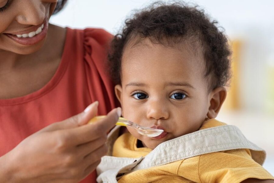 A mom feeds her baby a spoonful of baby food.