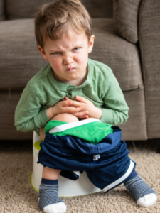 A toddler sits on his potty chair.