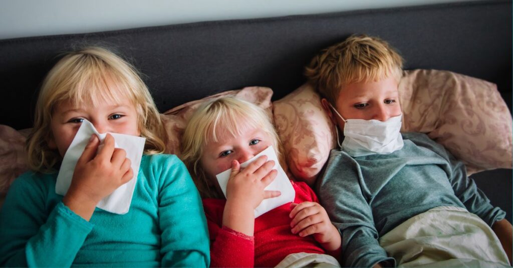 Three sick kids lay in bed together.