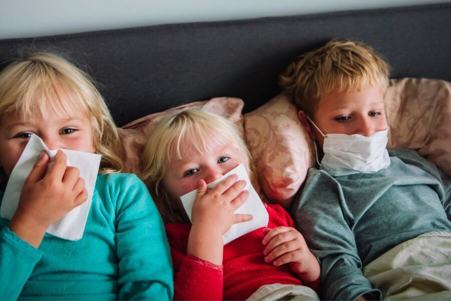 Three sick kids lay in bed together.