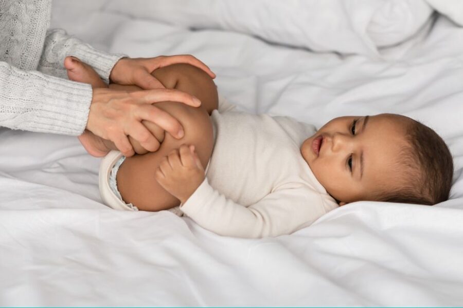 A mom gently presses her baby's legs into their stomach to help relieve constipation.