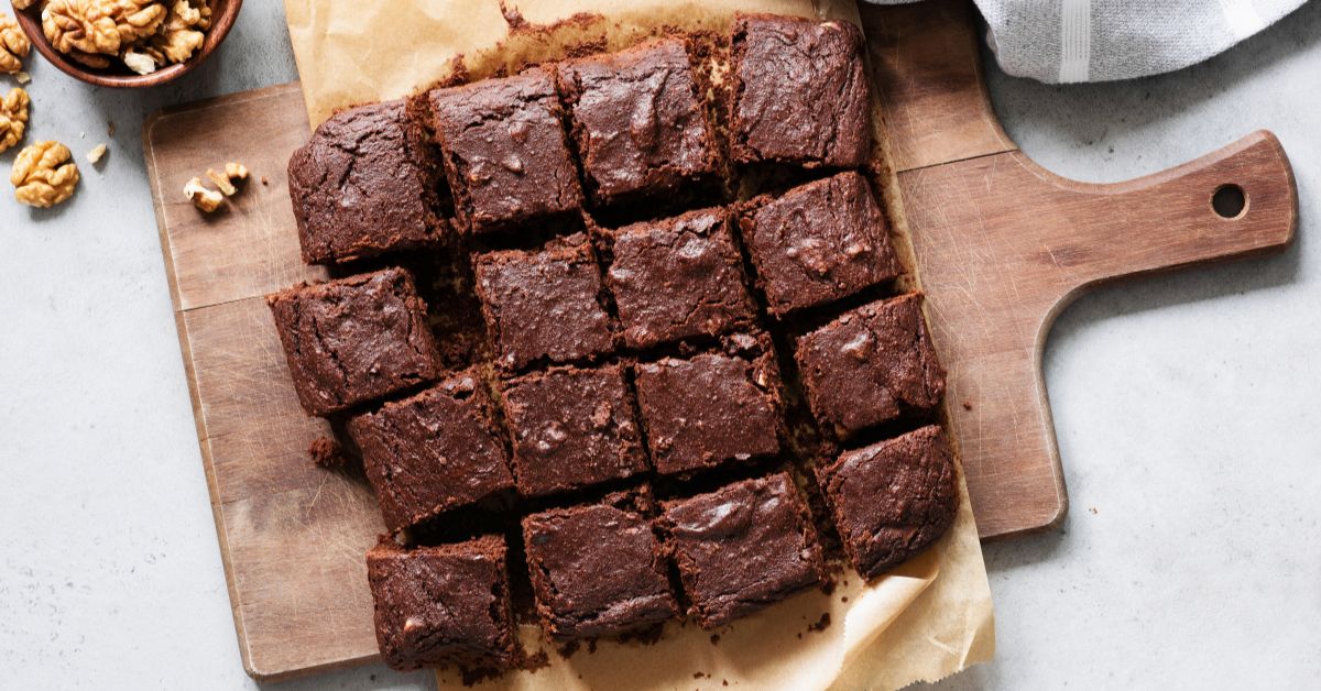 Several homemade brownies on a wooden cutting board.