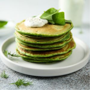 Green pancakes make from spinach on a white plate.
