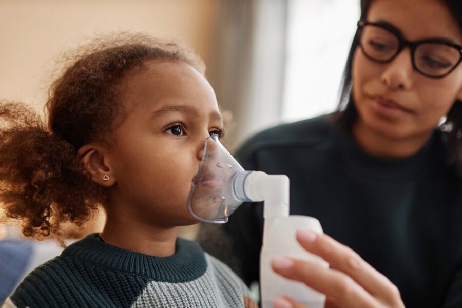 A girl breathes into a nebulizer mask.