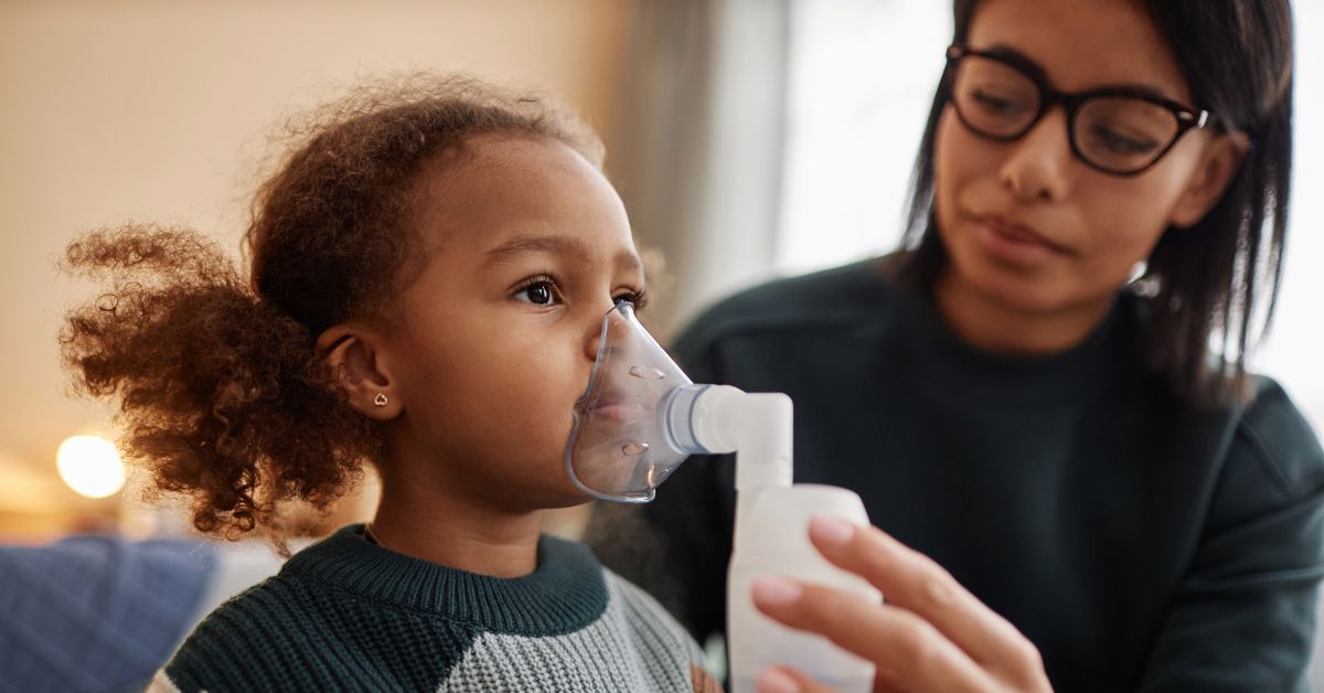 A girl breathes into a nebulizer mask.