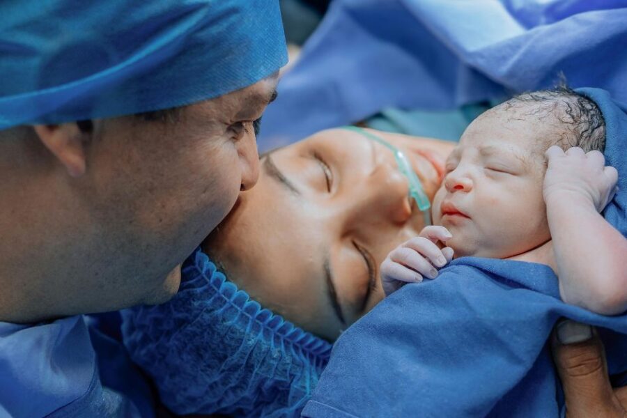 Parents hold their newborn baby immediately after a c-section.