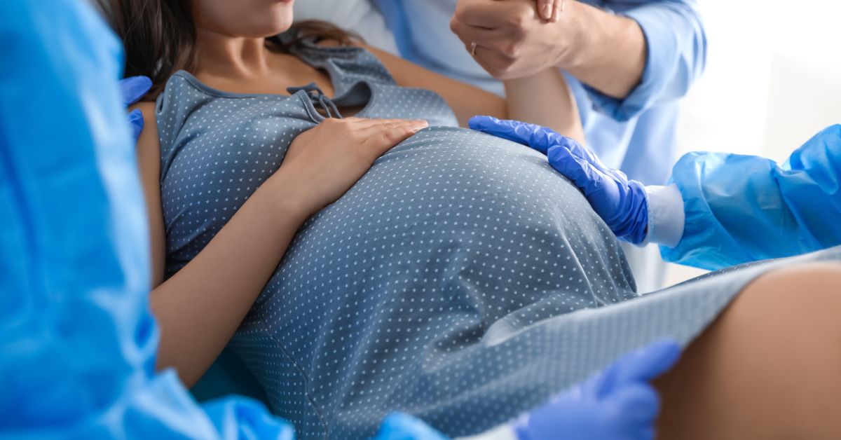 A woman giving birth is surrounded by medical professionals.