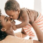 A mom holds her baby in the air.