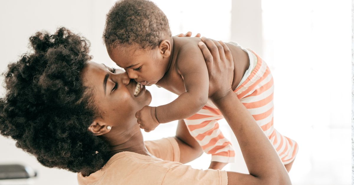 A mom holds her baby in the air.