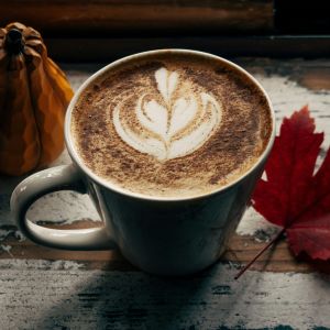 A cup of coffee with cream on a wooden counter.
