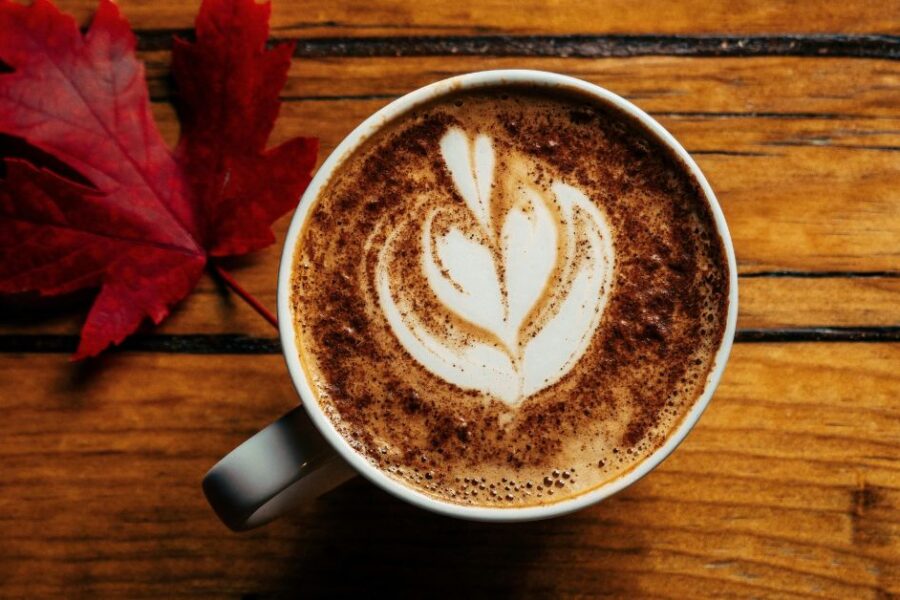A cup of coffee with cream on a wooden counter.