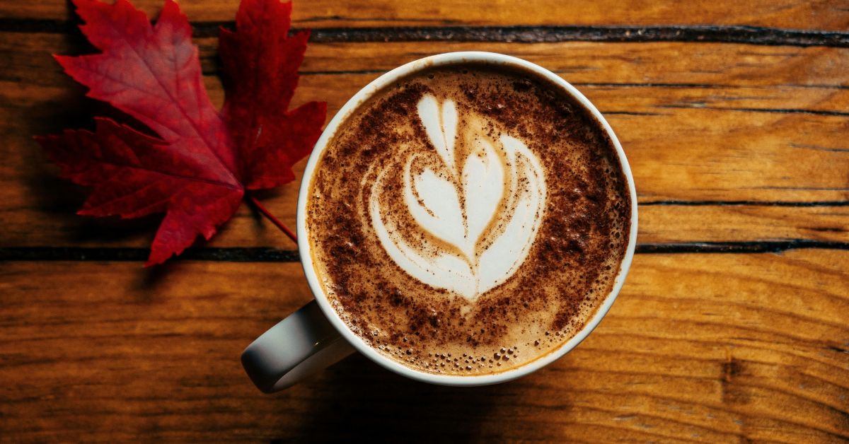A cup of coffee with cream on a wooden counter.