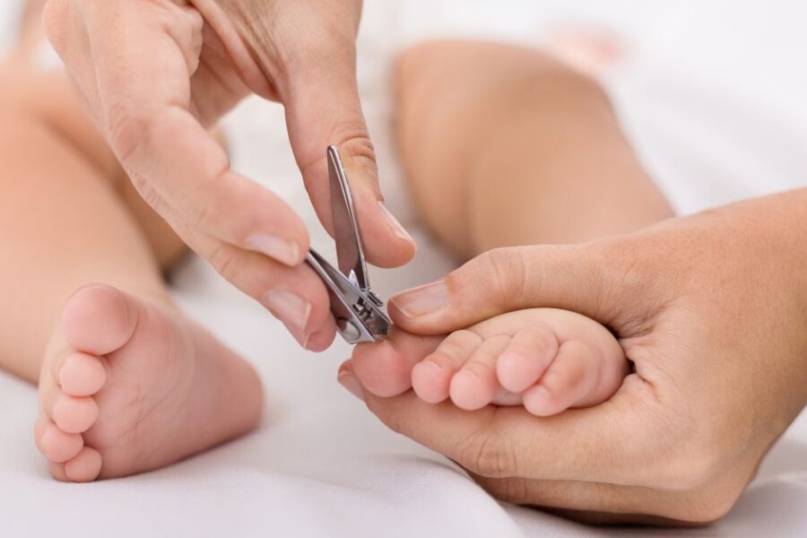 A mother clips her baby's toenails.