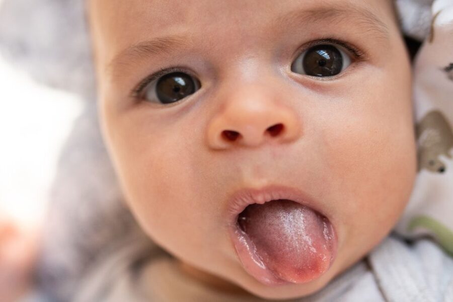 An infant sticks his tongue out.