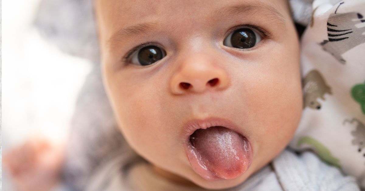 An infant sticks his tongue out.