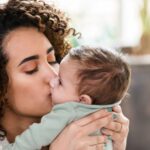 A mother kisses her baby's face.