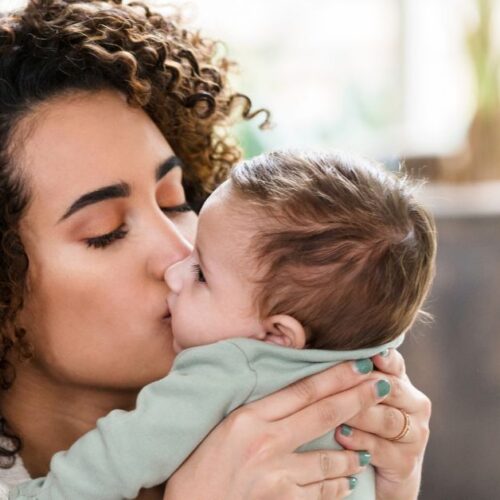 A mother kisses her baby's face.