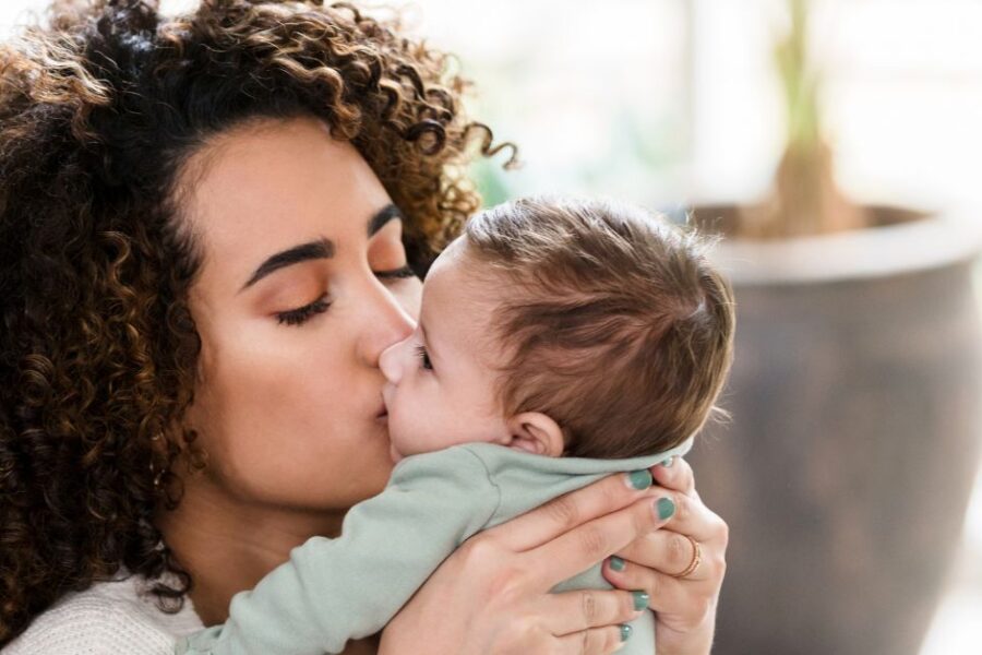 A mother kisses her baby's face.