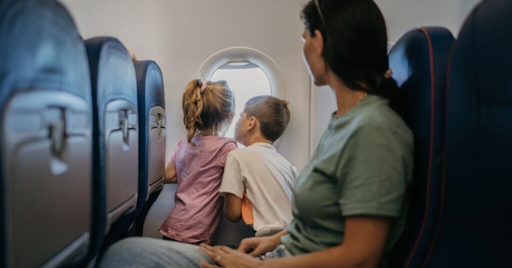 Children on an airplane look out the window.