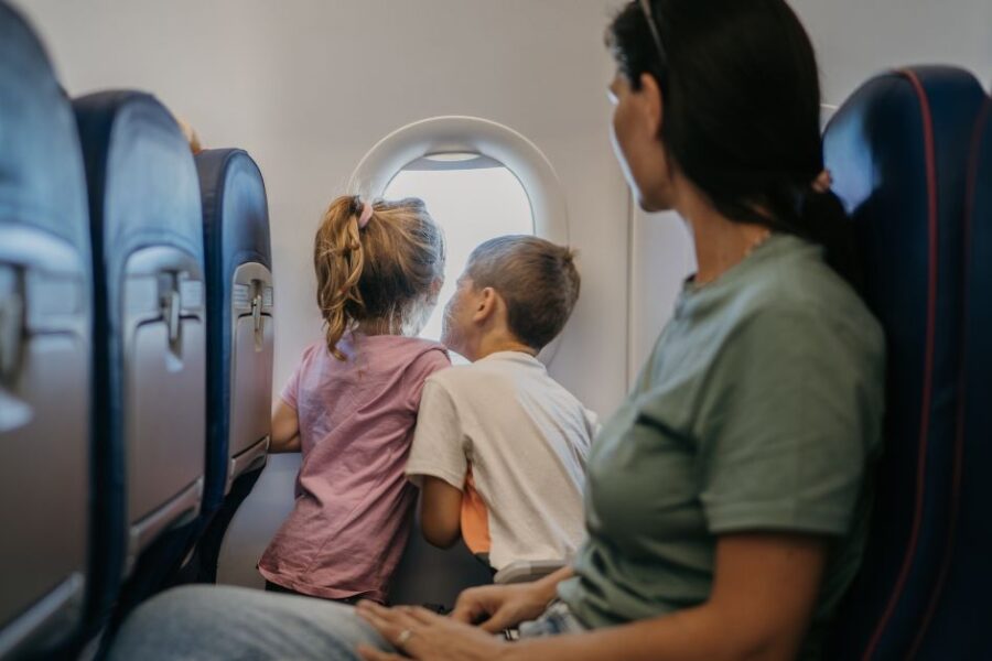 Children on an airplane look out the window.