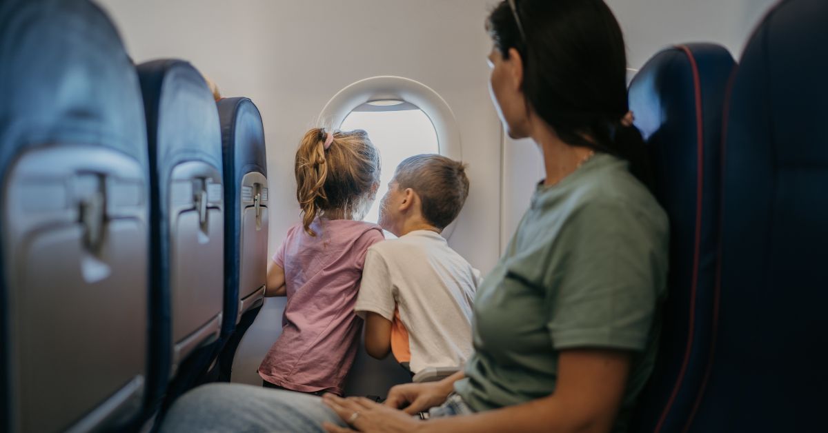 Children on an airplane look out the window.