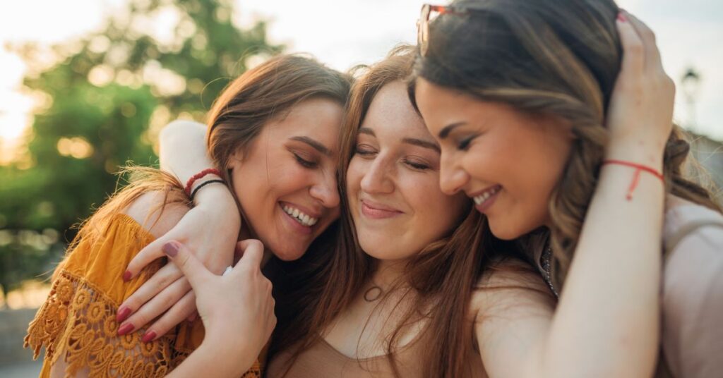 Three teenage girls hug each other.