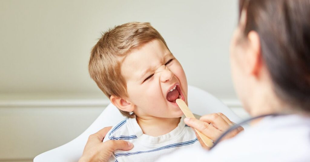 A doctor checks a boy's sore throat.