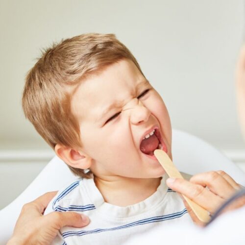 A doctor checks a boy's sore throat.