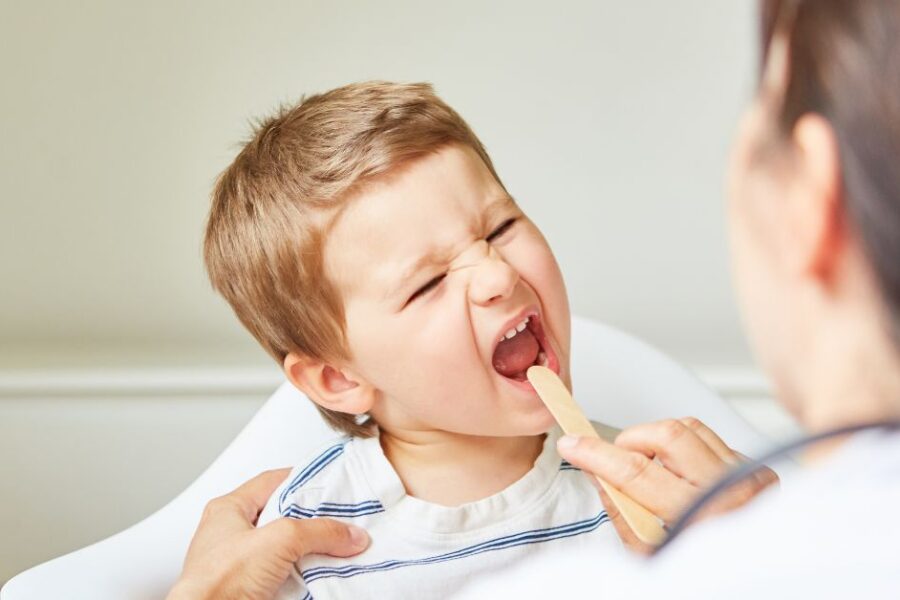 A doctor checks a boy's sore throat.