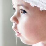 A baby girl has drool hanging from her mouth.