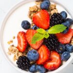 A bowl of yogurt with fruit and granola.