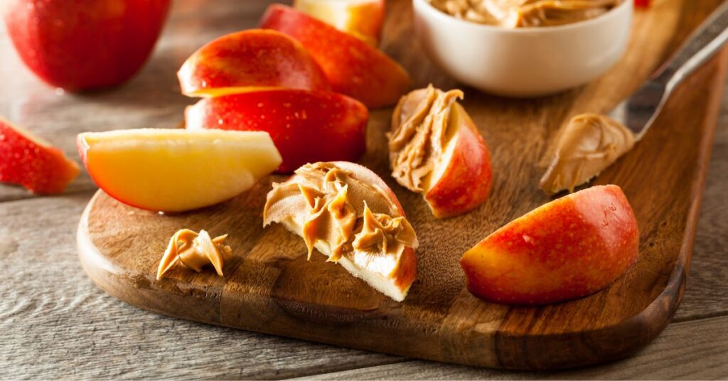 Apple slices with dabs of peanut butter on a wooden cutting board.