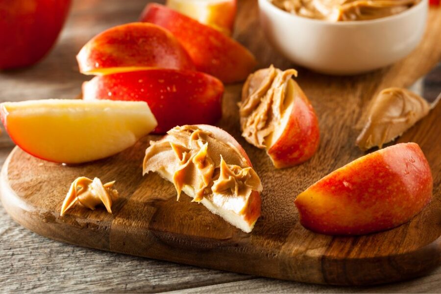 Apple slices with dabs of peanut butter on a wooden cutting board.