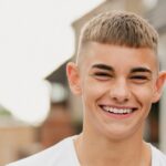 A teenage boy smiles while walking outdoors.