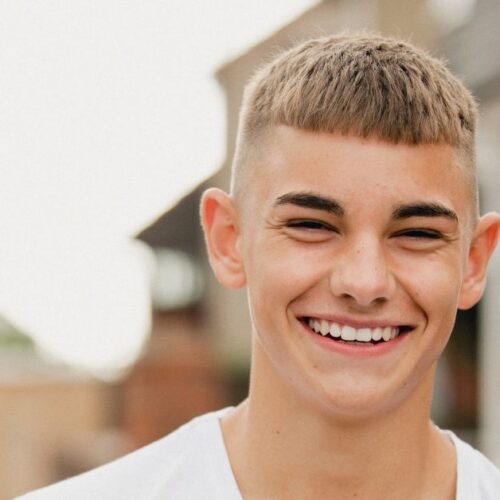 A teenage boy smiles while walking outdoors.